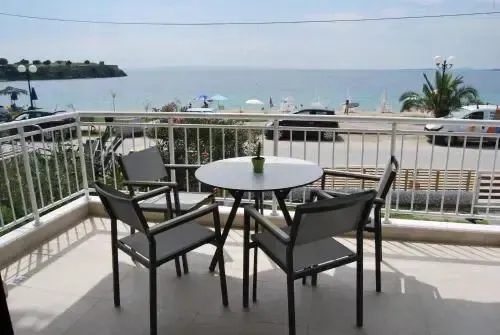 Une table ronde et des chaises en métal sur une terrasse ensoleillée avec vue sur la mer.