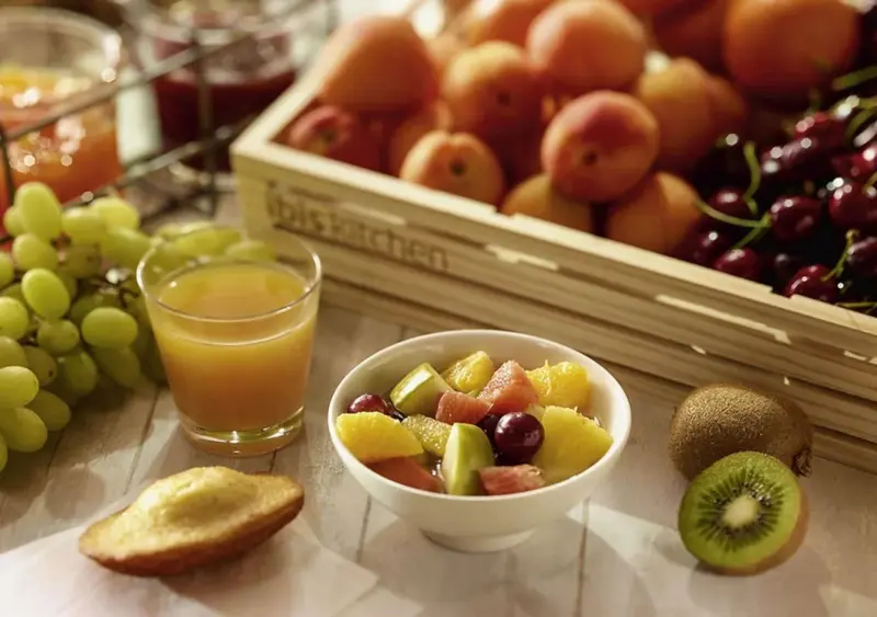 Assortiment de fruits frais et de viennoiseries sur une table claire.