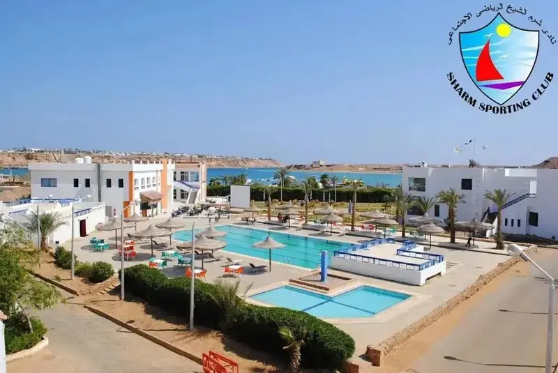 Vue aérienne d'un complexe hôtelier avec piscine et bâtiments blancs.
