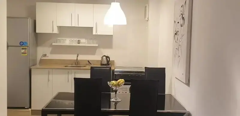 Une cuisine moderne s'ouvre sur un coin repas avec une table et des chaises.
