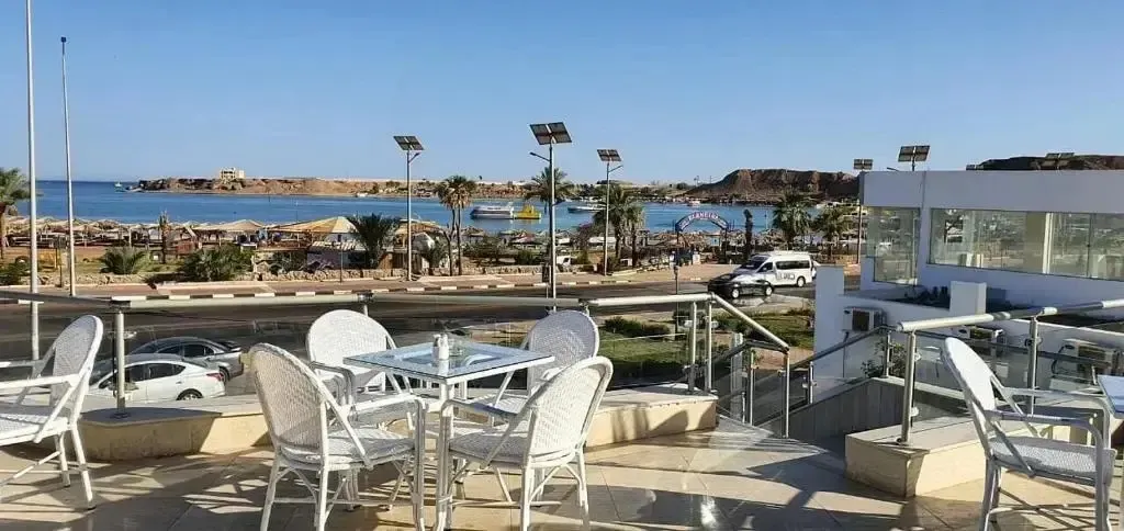 Terrasse aménagée avec tables et chaises donnant sur la mer et une plage.
