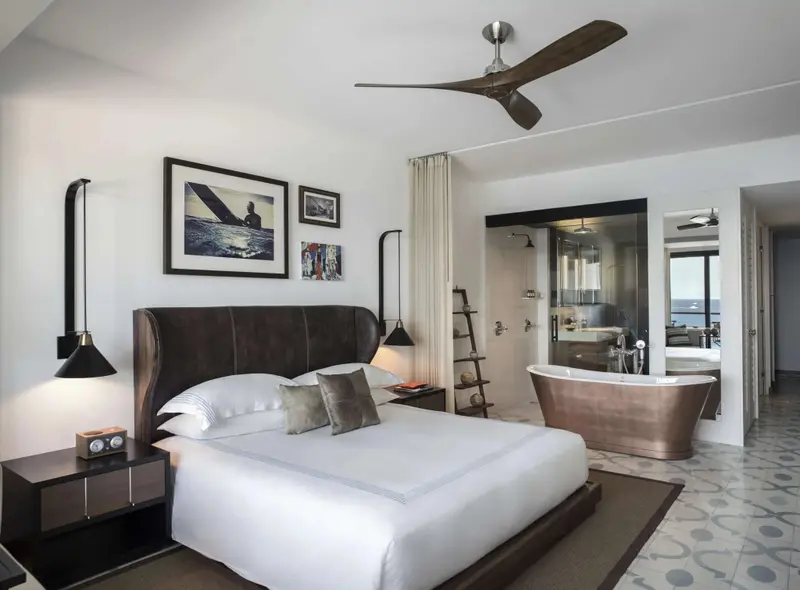 Une chambre lumineuse avec un grand lit et une baignoire îlot.