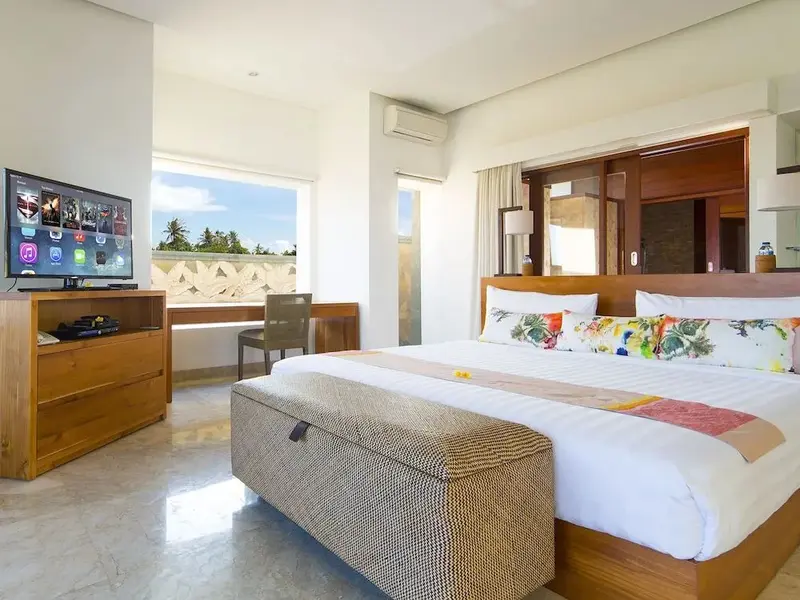 Une chambre lumineuse avec un grand lit et une vue sur la végétation.