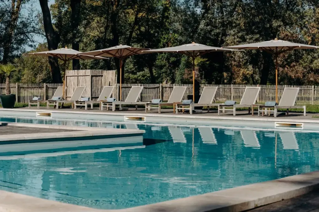 Transats et parasols bordent une piscine rectangulaire aux eaux turquoise.