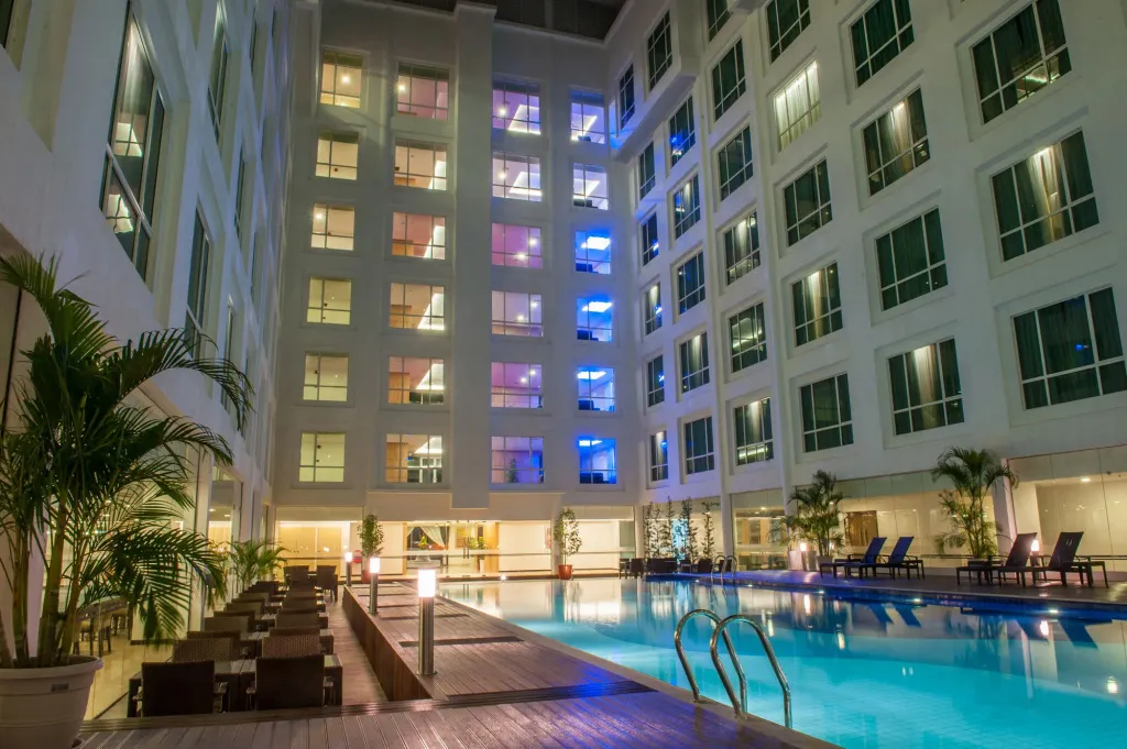 Une piscine illuminée au centre d'une cour intérieure d'hôtel.