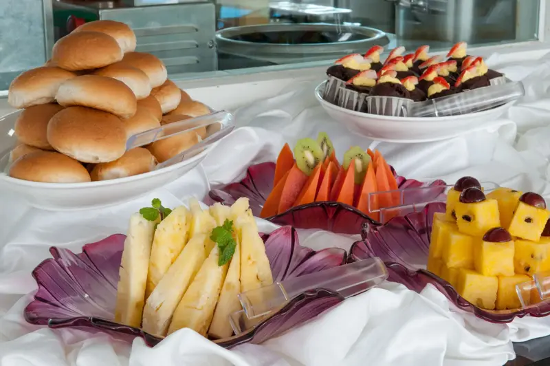 Assortiment de viennoiseries et de fruits frais présentés sur un buffet.