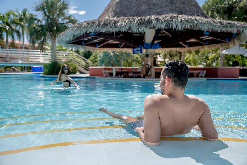 Deux personnes se relaxent au bord d'une piscine ensoleillée.