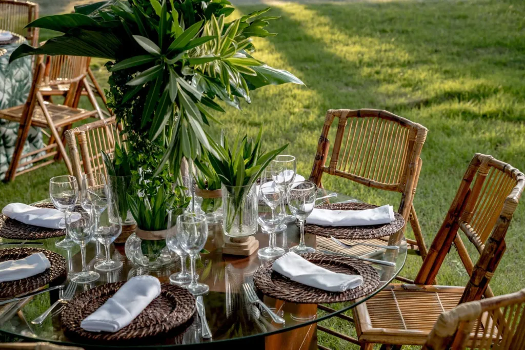 Une table ronde est dressée à l'extérieur avec des couverts et de la vaisselle.