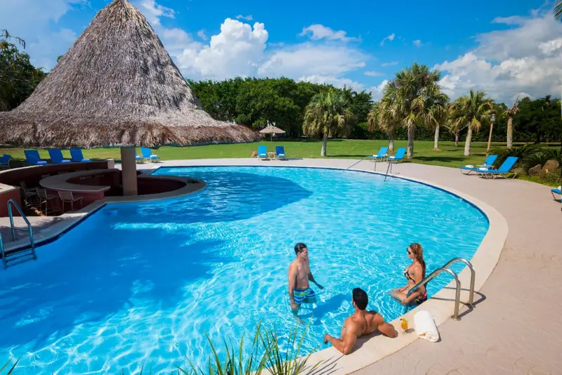 Une piscine bleue bordée de transats et d'un bar en plein air.