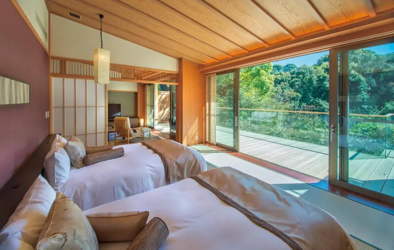 Une chambre lumineuse avec deux lits et un accès à une terrasse.