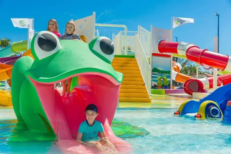 Des enfants s'amusent sur des toboggans aquatiques colorés dans une piscine.