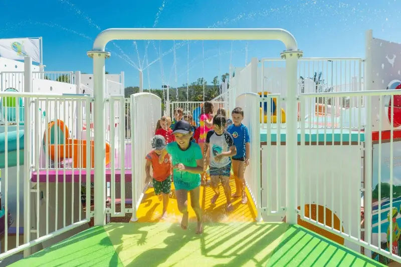 Des enfants courent et jouent dans un parc aquatique coloré.