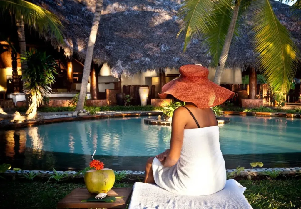 Une personne assise au bord d'une piscine avec une boisson exotique.