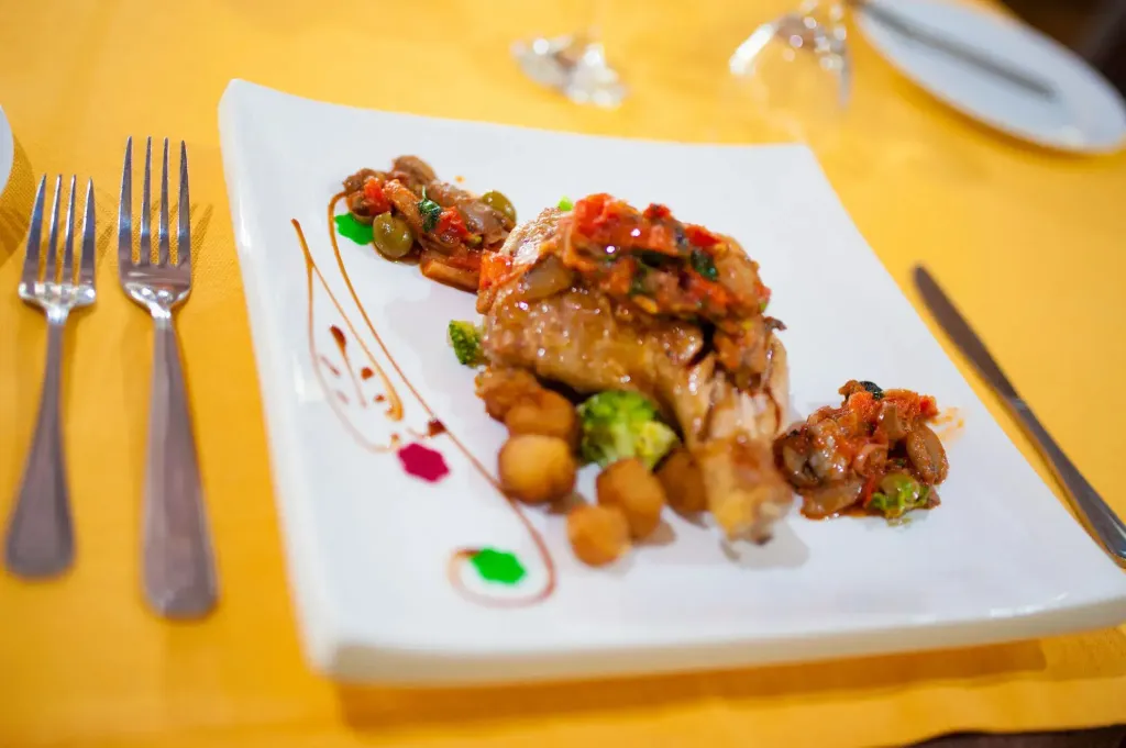 Assiette de viande accompagnée de légumes et de sauce décorée.