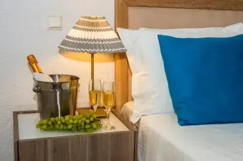 Une bouteille de champagne et des verres sont posés sur une table de chevet éclairée par une lampe.