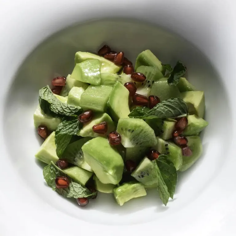 Salade de concombres, kiwis et grenades frais, parsemée de menthe.