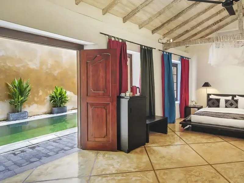 Une chambre lumineuse s'ouvre sur une piscine par de larges baies vitrées.