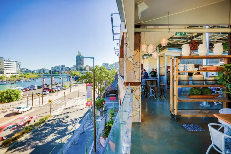 Terrasse ensoleillée donnant sur une ville portuaire animée.
