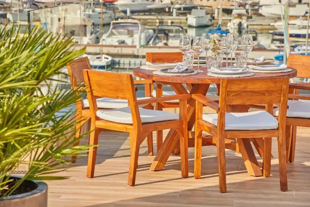 Une table ronde en bois est mise en scène avec de la vaisselle et des couverts.