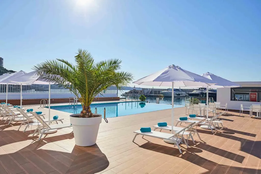Terrasse avec piscine et transats sous des parasols blancs.