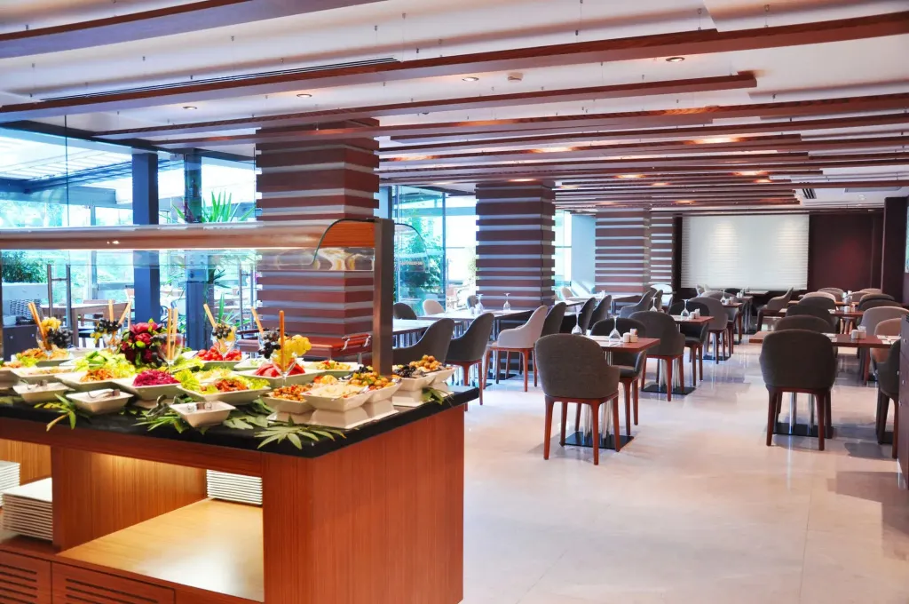Un buffet de salades colorées est présenté dans une salle de restaurant lumineuse et moderne.