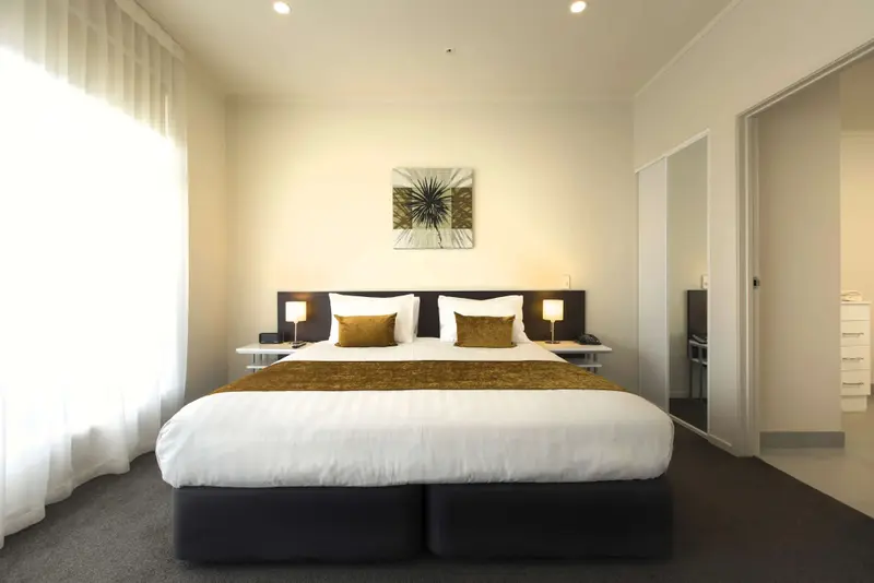 Une chambre lumineuse avec un grand lit recouvert d'une courtepointe.