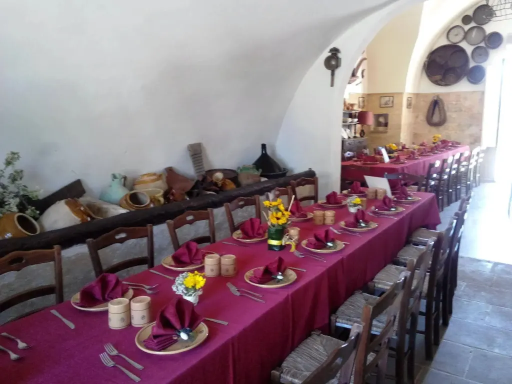 Une longue table dressée pour un repas dans une salle voûtée.
