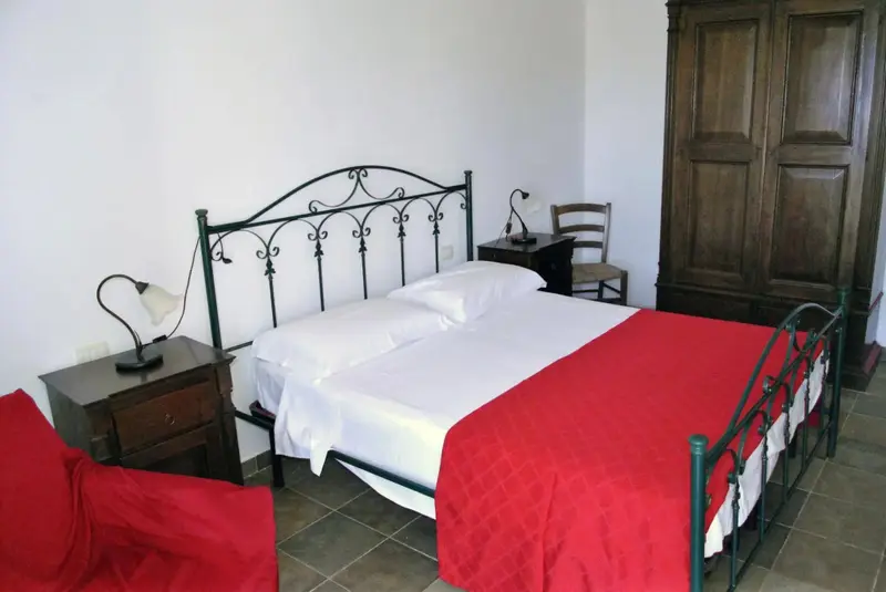Une chambre lumineuse avec un lit recouvert d'une courtepointe rouge et blanche.