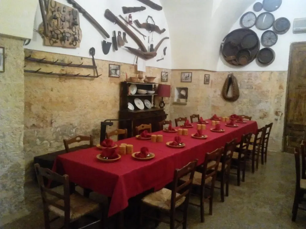 Une longue table dressée dans une salle voûtée décorée d'outils agricoles.