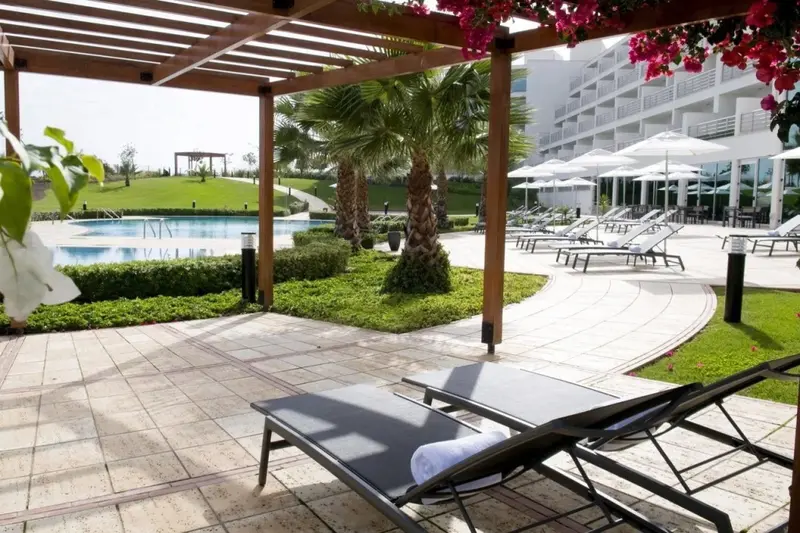 Transats disposés sur une terrasse ensoleillée près d'une piscine.