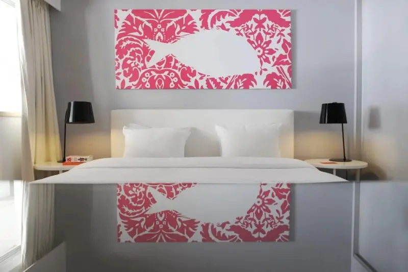 Une chambre lumineuse avec un grand lit recouvert d'une courtepointe blanche et de coussins.