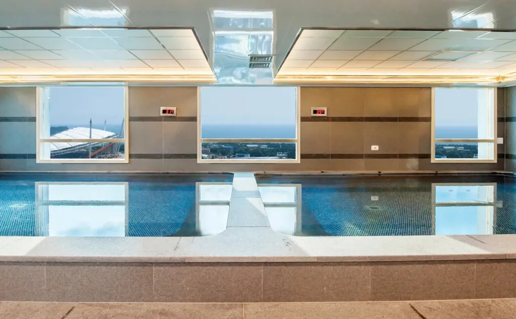 Une piscine intérieure avec vue sur la mer à travers de grandes fenêtres.