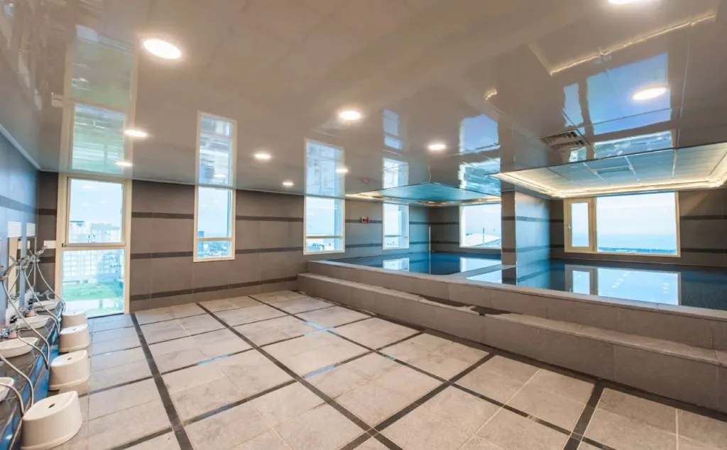 Une piscine intérieure lumineuse avec une vue sur la mer par de grandes fenêtres.