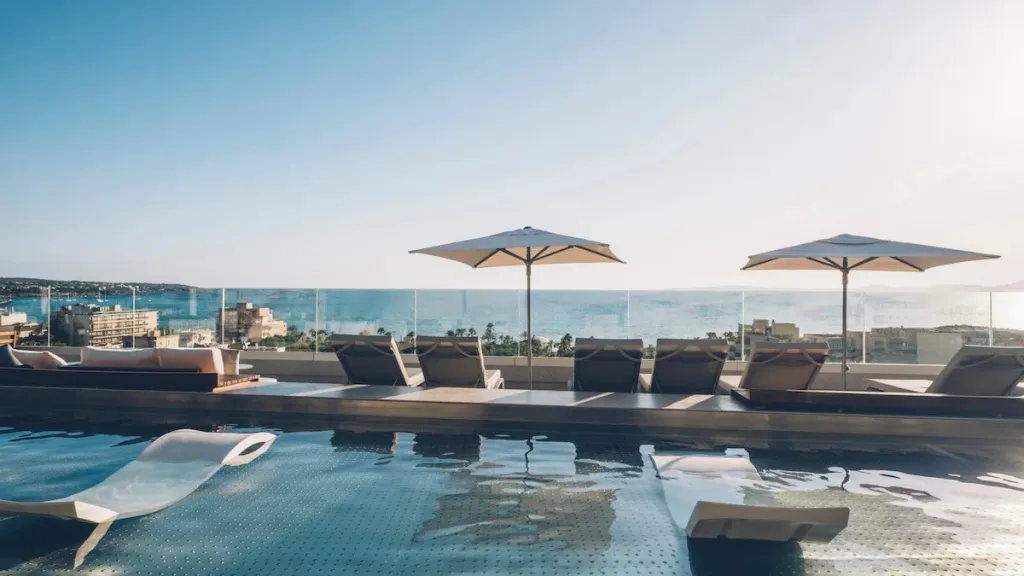Transats et parasols bordent une piscine à débordement avec vue sur la mer.