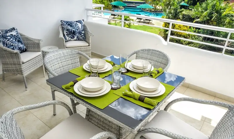 Une table est dressée pour un repas sur une terrasse ensoleillée.