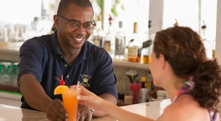 Un barman souriant sert une boisson colorée à une cliente.