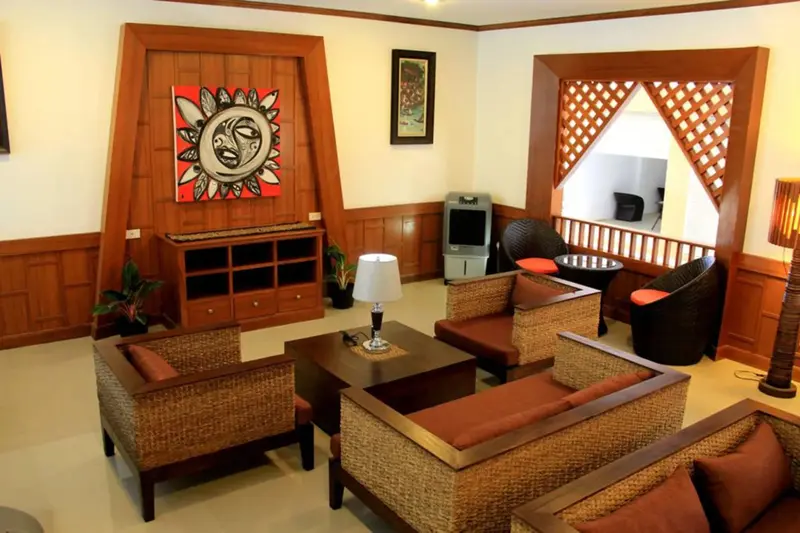 Un espace de détente intérieur avec des fauteuils en rotin et une décoration murale.