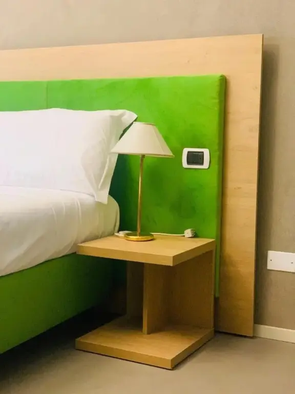 Une chambre lumineuse avec un lit recouvert de draps blancs et une table de chevet en bois.