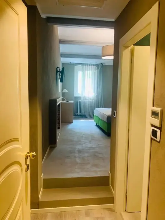 Une chambre lumineuse avec un lit vert et une fenêtre.
