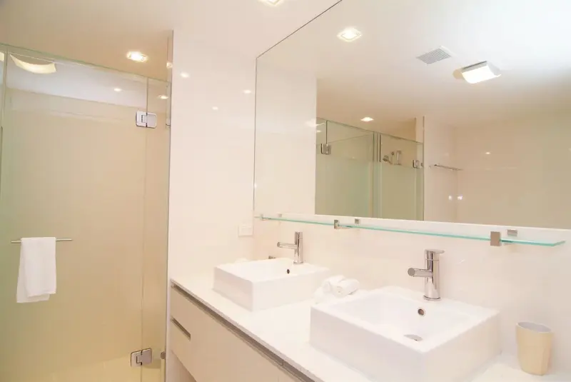Une salle de bain moderne avec deux vasques et une douche vitrée.