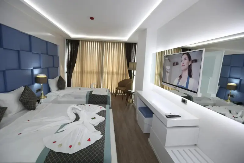 Une chambre lumineuse avec deux lits décorés de serviettes en forme de cygne.