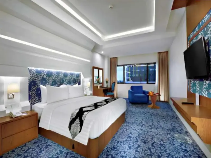 Une chambre lumineuse avec un grand lit et un coin salon.