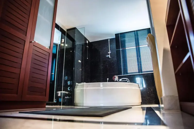 Une baignoire blanche se trouve dans une salle de bain carrelée sombre.