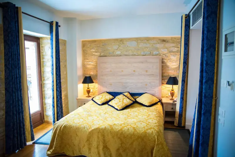 Une chambre lumineuse avec un grand lit recouvert d'une courtepointe jaune et de coussins décoratifs.