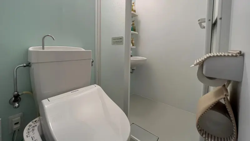 Une salle de bain claire avec des sanitaires blancs et un porte-serviettes en tissu.