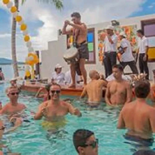 Des personnes se baignent et s'amusent dans une piscine ensoleillée.