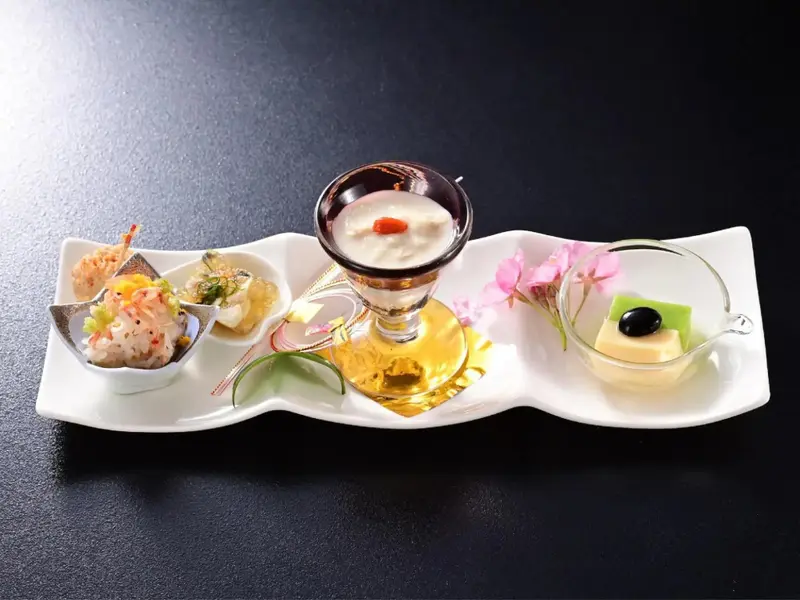 Assortiment de petites préparations culinaires disposées sur une longue assiette blanche.