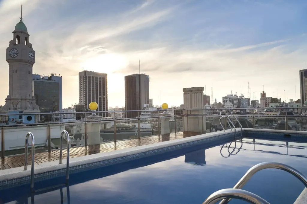 Piscine sur toit-terrasse avec vue sur la ville et le coucher de soleil.