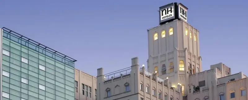 Bâtiment moderne et tour illuminée au crépuscule.