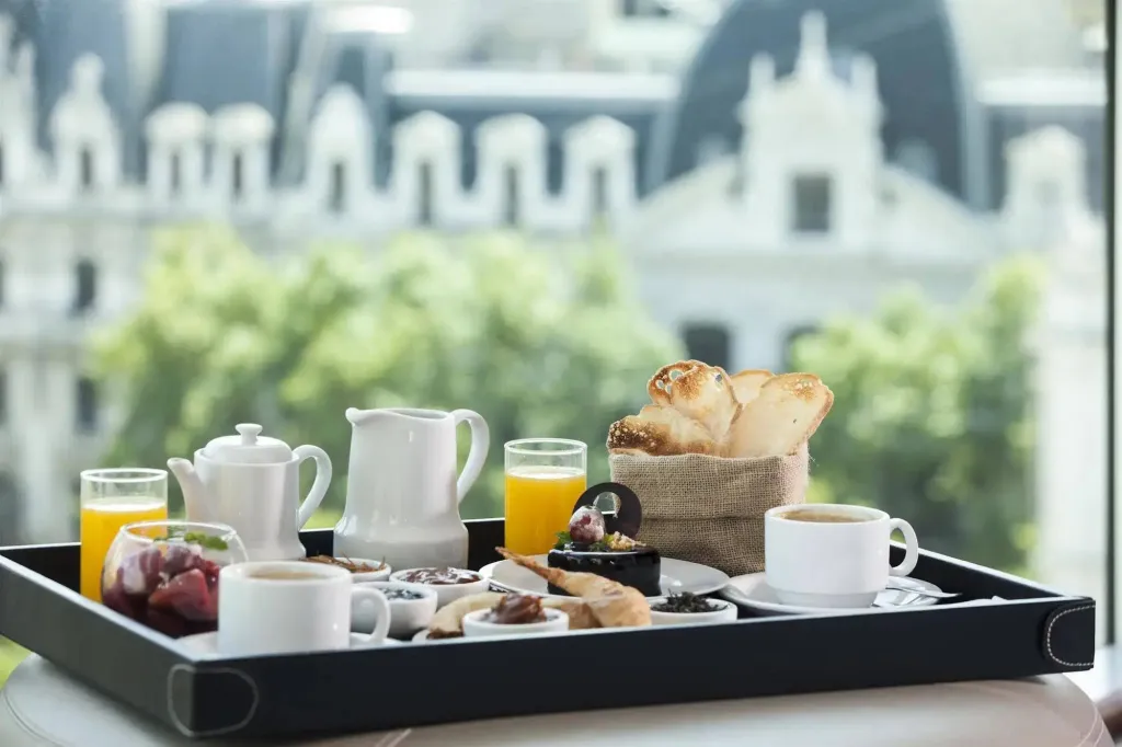 Un plateau de petit-déjeuner est présenté sur une table avec une vue floue sur un bâtiment en arrière-plan.